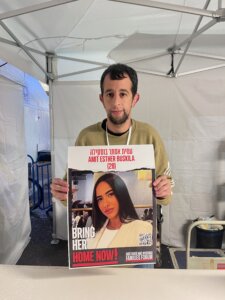 Tal Schechter est bénévole à Hostage Square et distribue des affiches d'otages afin de maintenir la pression pour leur libération.  Parmi les personnes figurant sur les affiches se trouve son meilleur ami, Amit Buskila.