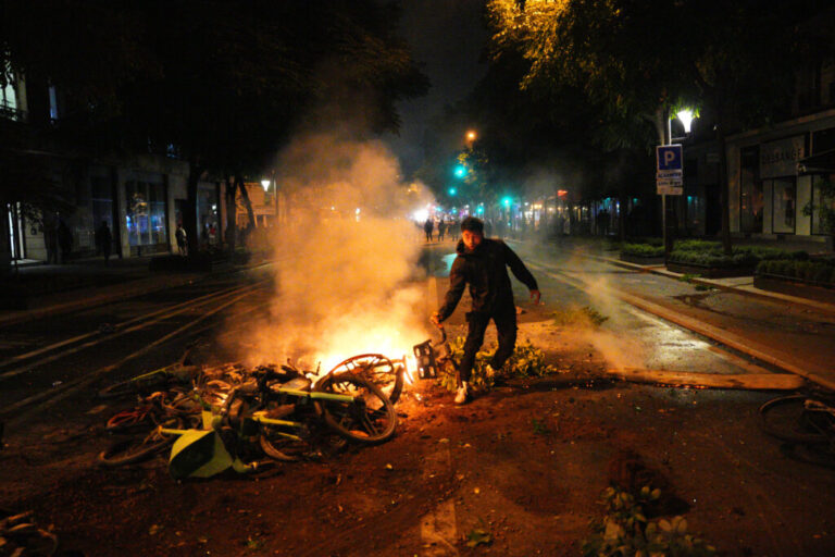 A man stands next to burning e-bikes during a protest following the legislative election results on July 8, 2024 in Paris, France.