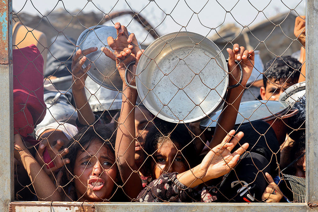 Les Palestiniens, principalement des enfants, poussent pour recevoir un repas chaud dans une cuisine caritative dans la région de Mawasi de Khan Yunis dans le sud de Gaza.