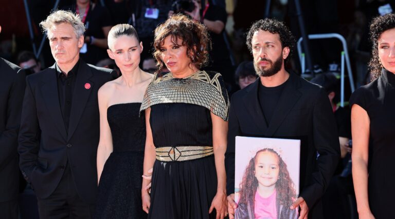 Filmmakers hold a photo of Hind Rajab at a red-carpet premiere