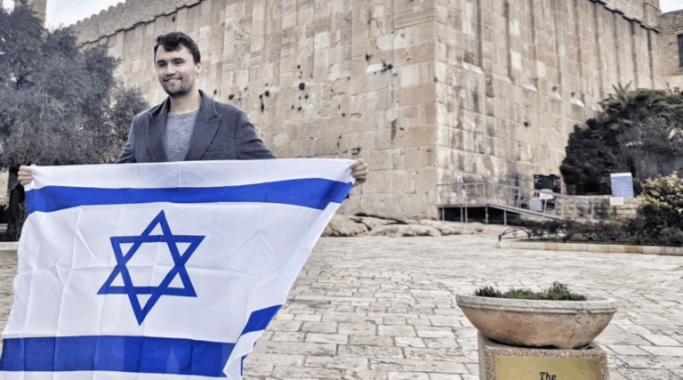 Charlie Kirk holds an Israeli flag outside the Cave of the Patriarchs in the West Bank.
